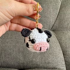 a hand holding a keychain with a small cow on it