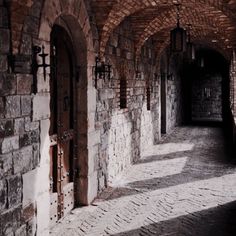 an empty hallway with brick walls and arched doorways