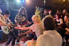 a group of people standing around each other with guitars in their hands and one person playing the guitar