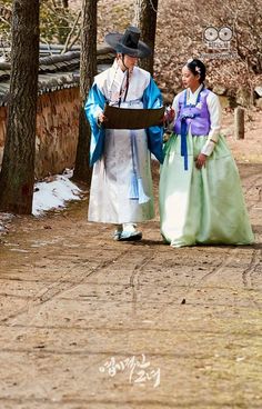 two people dressed in traditional japanese clothing standing next to each other on a dirt road