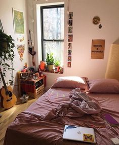 an unmade bed in a small room with lots of clutter