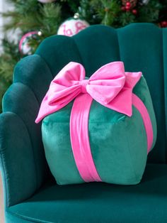 a green chair with a pink bow on it's back and christmas tree in the background