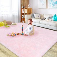 a baby sitting on the floor playing with blocks and building toys in a living room