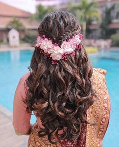 the back of a woman's head with flowers in her hair near a swimming pool