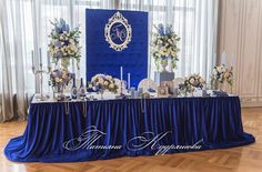 the table is set up with blue linens and white flowers, candles and centerpieces