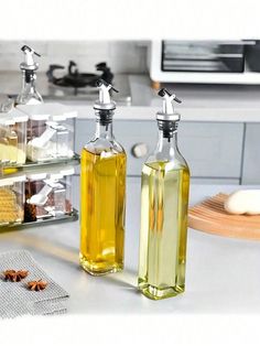 two bottles of olive oil sitting on top of a counter next to other kitchen items