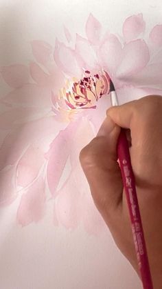 a person is painting a flower on the wall with pink paint and a red pencil