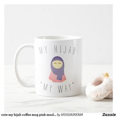 a white coffee mug with a cartoon character on it next to a donut that says, my hijab is my way