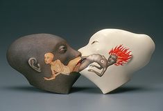 two ceramic heads with faces painted to look like they are kissing each other on the nose