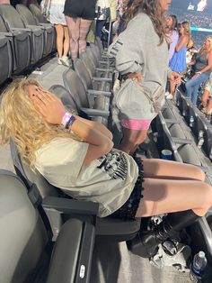 a woman sitting in the bleachers at a baseball game with her hand on her face