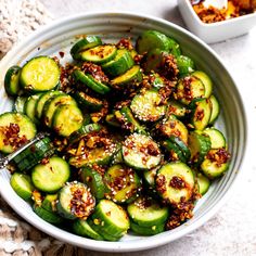 a white bowl filled with sliced cucumbers and seasoning