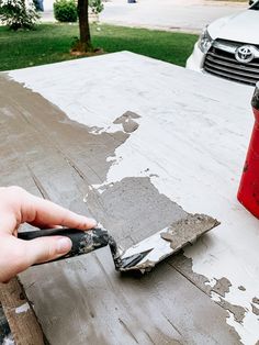 a person is painting the outside of a house with white paint on it and a red fire extinguisher nearby