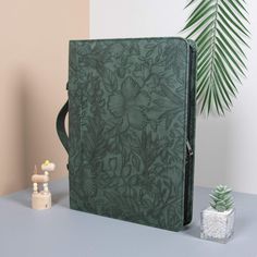 a green notebook sitting on top of a table next to a potted plant