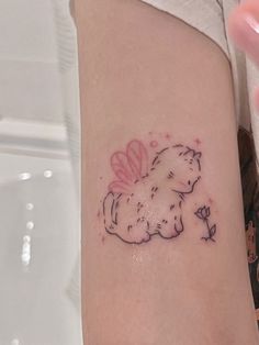 a woman's arm with a small tattoo of a dog on the left side