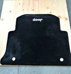 a black floor mat with the word need written on it in white lettering, sitting on top of a wooden board