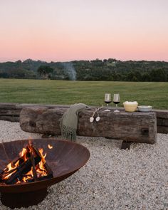 a fire pit sitting on top of gravel next to a wooden fence and grass field