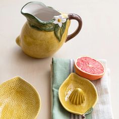 a yellow pitcher and two bowls with grapefruits on the side next to each other