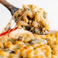 a spoon full of macaroni and cheese being lifted from the casserole dish