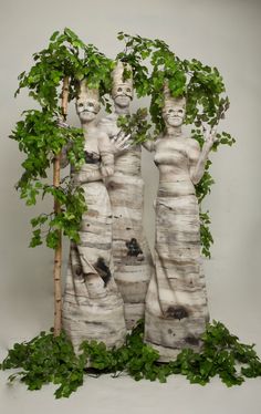 two statues made out of tree trunks with green leaves growing on the top and bottom