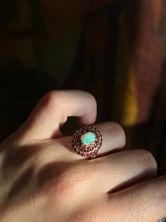 A delicious mid-century adornment, with a luminescent dazzle! Crafted circa 1970’s in 18 carat gold, this Opal and Ruby ring is a vibrant cluster of sparkles! No matter how you wear this ring, it is a feast for the eyes. The crackling colors of this exceptional opal pick up beautifully against the vibrant jam tones of the double ruby halo. Double prongs complete the regal look of the ring, creating a sophisticated yet timeless silhouette. One of the loveliest details is the undercarriage; with its scrolling foliate design and slight open back, it is a wonderful example of the classic 1970’s ring design. A wonderful vintage treasure, perfect for the antique connoisseur and romantic alike! Materials and Features: 18ct, Opal, Ruby Marks: 18K Age/Origin: 1970’s, American Measurements: Size 5, Dazzling 17 Jewels Cluster Ring, 14k Gold Cluster Ring Hallmarked, Vintage Cluster Ring With Halo As Gift, Vintage Halo Cluster Ring As Gift, Vintage Halo Cluster Ring Gift, Vintage Yellow Gold Halo Jewelry, Vintage Ruby Ring With Multi-stone For Collectors, Antique Ruby Ring With Multi-stone, Antique Multi-stone Ruby Ring