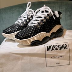 Moschino Sneakers, Made In Italy, Are Renowned For Their Quality And Creative Designs. These Shoes Are Made From Textile Fibers And Feature A Quilted Design With The Brand Logo. They Come In A Solid Color With Laces, A Round Toe, And A Wedge Heel. The Rubber Sole Has A Platform Height Of 1.17 Inches And A Heel Height Of 1.95 Inches. It Comes With Dust Bag And Box (The Box Is Not In Perfect Condition!) Designer High-top Sneakers With Studded Outsoles, Chic Leather Sneakers With Perforations, Chic Low-top Sneakers With Rubber Sole, Chic Low-top Sneakers With Perforations, Chic Leather Sneakers With Studded Rubber Outsoles, Chic Leather Sneakers With Laces, Chic Lace-up Sneakers With Contrast Sole, Chic Sneakers With Rubber Sole And Round Toe, Chic Sneakers With Textured Sole And Round Toe