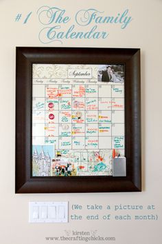 the family calendar is hanging on the wall in front of a framed photo with words above it