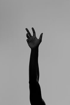 a black and white photo of a person reaching up to catch a frisbee