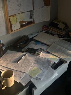 a cluttered desk with many papers and a calculator on it, in an office