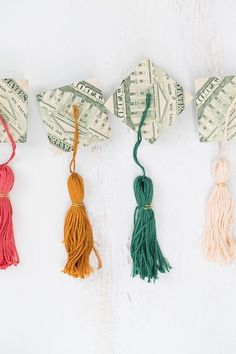 four pieces of origami with tassels hanging from them on a white background