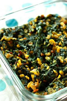 a glass dish filled with corn and spinach on top of a polka dot table cloth