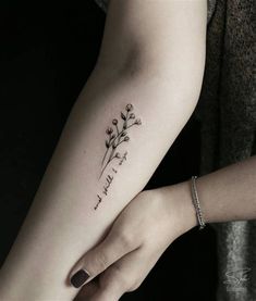 a woman's arm with a small flower tattoo on the left side of her arm