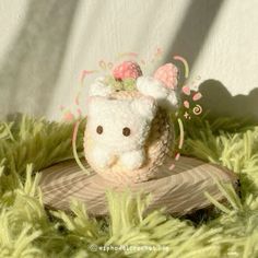 a small stuffed animal with a bow on it's head sitting on a piece of wood