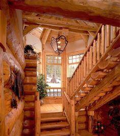 a wooden staircase in a log cabin with wood railings and handrails leading up to the second floor