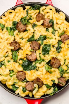 a skillet filled with pasta, sausage and spinach