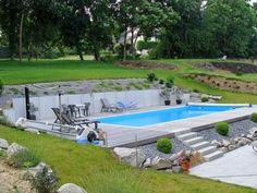 a backyard with a pool surrounded by rocks and trees