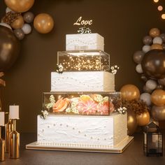 a three tiered wedding cake with gold and silver balloons in the background, surrounded by confetti