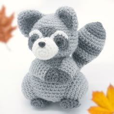 a crocheted stuffed animal sitting on top of a white table next to leaves