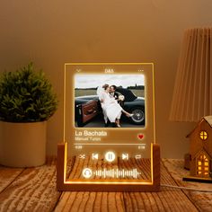 an electronic photo frame sitting on top of a wooden table next to a potted plant