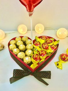 a heart shaped box filled with chocolates next to other candies and lights on a table