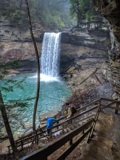 two people are climbing stairs near a waterfall