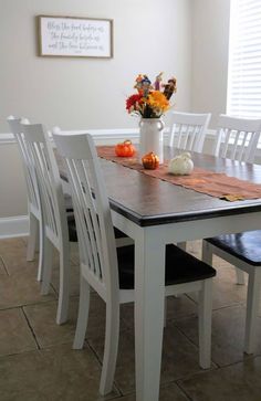 a dining room table with white chairs and fall decorations