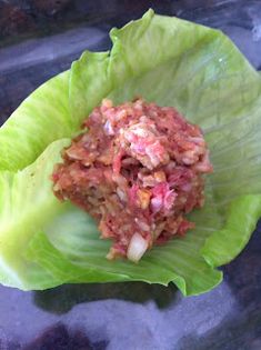 a lettuce leaf filled with food sitting on top of a glass countertop