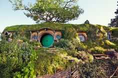 the hobbot house in new zealand is surrounded by greenery and has a green door