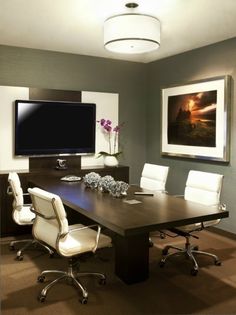 a large conference table with white chairs and a flat screen tv mounted on the wall