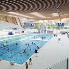 an indoor swimming pool with lots of people in the water and onlookers