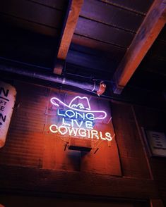 a neon sign that says long live cowgirls on the side of a building