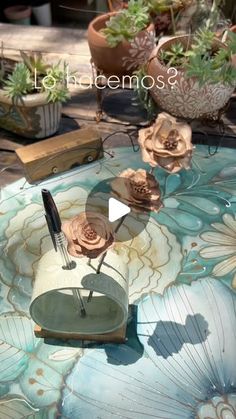 there is a glass table with flowers on it and some plants in the back ground