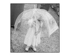 black and white photograph of a person holding an umbrella over their head while standing in the rain