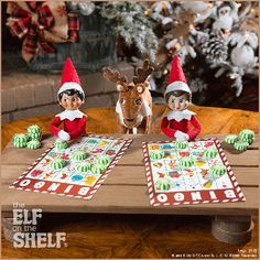 three elfs are sitting at a table with christmas cards and reindeer figurines