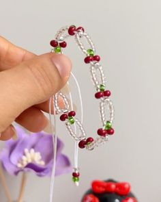 a hand holding a beaded bracelet next to a cake